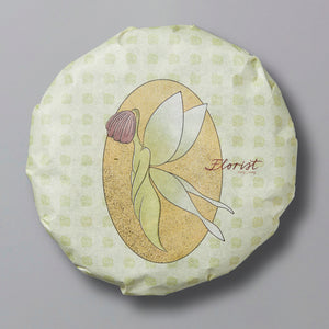 A pressed white tea cake with a floral design and the word 'Florist' printed on the top surface, against a patterned background.