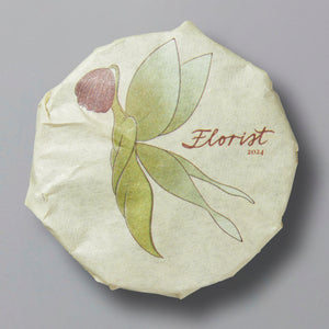 Florist 2024 white tea cake wrapped in paper featuring minimalist floral illustration and product name.