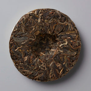 MADE-FOR-TV sheng puer tea cake showing compressed dark and golden tea leaves in traditional circular disc form