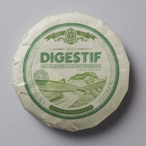 2023 Digestif shou puer tea cake with green circular label showing mountain landscape and rope border design