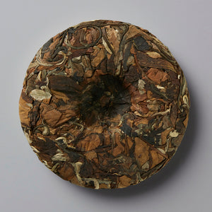 NOT FROM CONCENTRATE white tea cake disc showing compressed brown and golden tea leaves in circular pattern