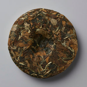 2023 NO SHADE white tea cake with variegated brown and silver leaves compressed into a round disc shape