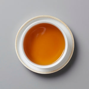 Top view of a white cup filled with amber-colored Sam’s Wa-Ko-Sha black tea on a matching saucer.