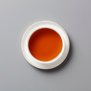 PANLAN 105 yancha oolong tea in white ceramic cup showing rich amber-colored liquor on grey background