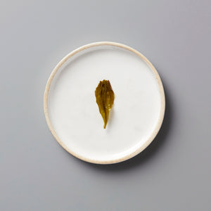 Lins Big Leaf dancong oolong tea leaf displayed on white ceramic plate, showing authentic dried leaf texture and color
