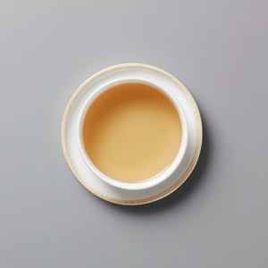 LINS DUCK dancong oolong tea in white ceramic cup with golden amber liquid against grey background
