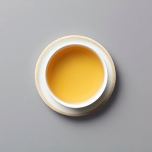 PANLAN QUE SHE yancha oolong tea in white ceramic cup showing golden amber liquid against grey background