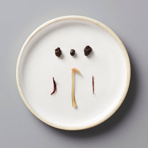 CURRANT tisane blend ingredients artfully arranged on white ceramic plate showing dried currants and herbs