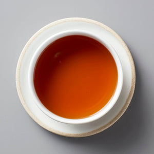 GAO WEN black tea in white ceramic cup showing rich amber-colored liquor against grey background