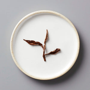 GAO WEN black tea leaves artistically arranged on white ceramic plate showing delicate twisted stems and leaves
