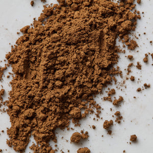 Houji Powder Hugo green tea powder scattered on white surface showing fine, rich brown texture and consistency