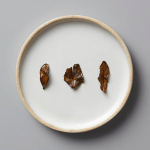 Kyobancha Nakai green tea leaves on white ceramic plate, displaying rich brown roasted color and flat leaf structure