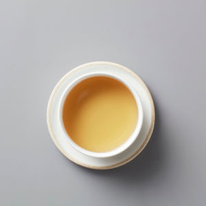 MA WEI MOONLIGHT white tea in ceramic cup, showing golden amber liquid from above view on grey background
