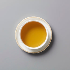 RAINIER tisane blend in white ceramic cup showing golden-orange liquor from above on grey background