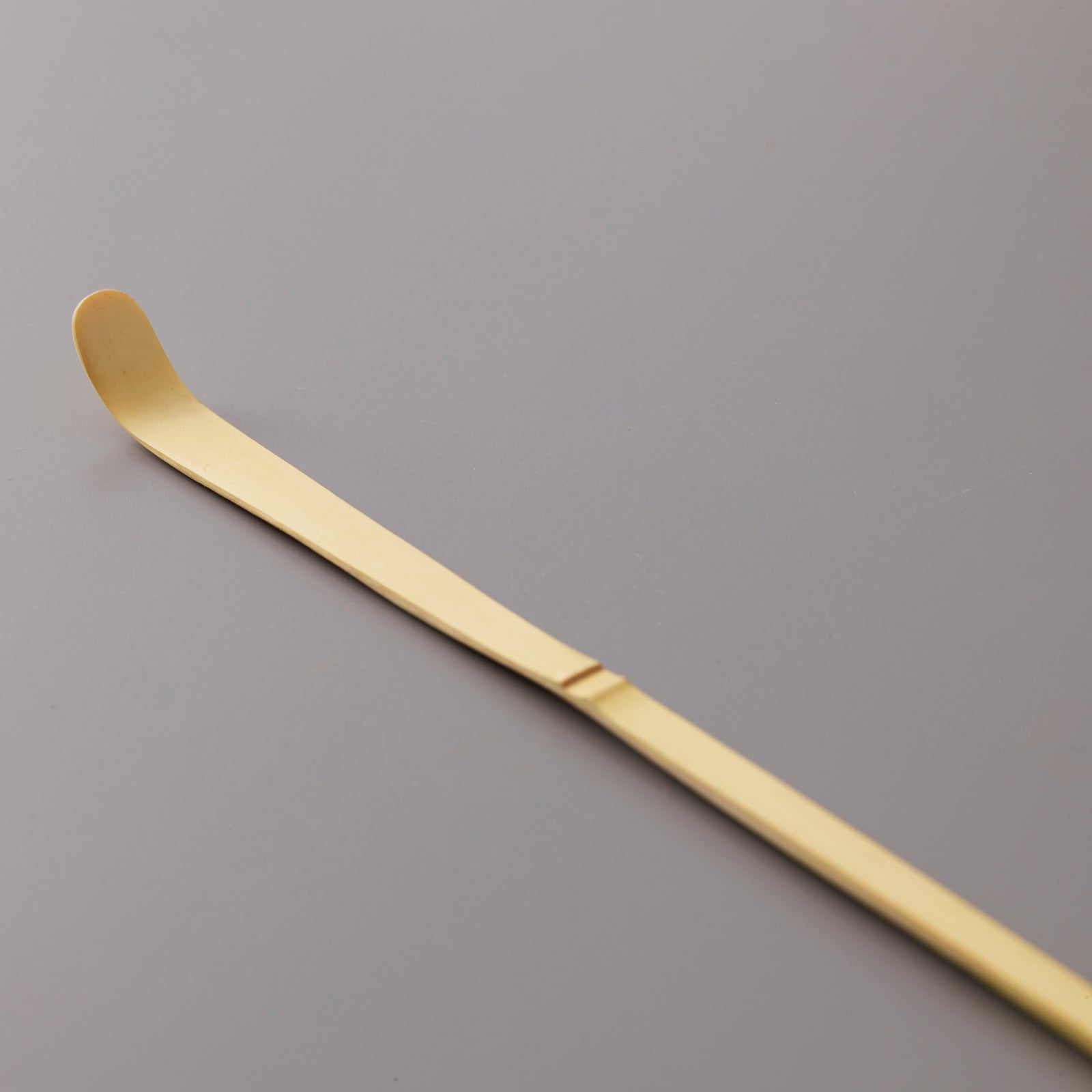 Traditional bamboo Matcha Scoop Chashaku with curved tip for precise tea measuring on grey background