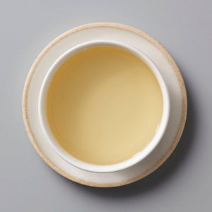 ANXI TGY oolong tea in white ceramic cup showing pale golden liquor against grey background