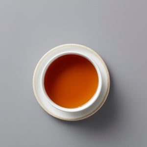 Vanilla Chai black tea blend in white ceramic cup showing rich amber-colored liquor on grey background