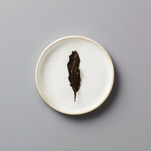 Zi Ran Smoke black tea leaf on white ceramic plate showing natural artisanal lapsang souchong from Tongmu, China