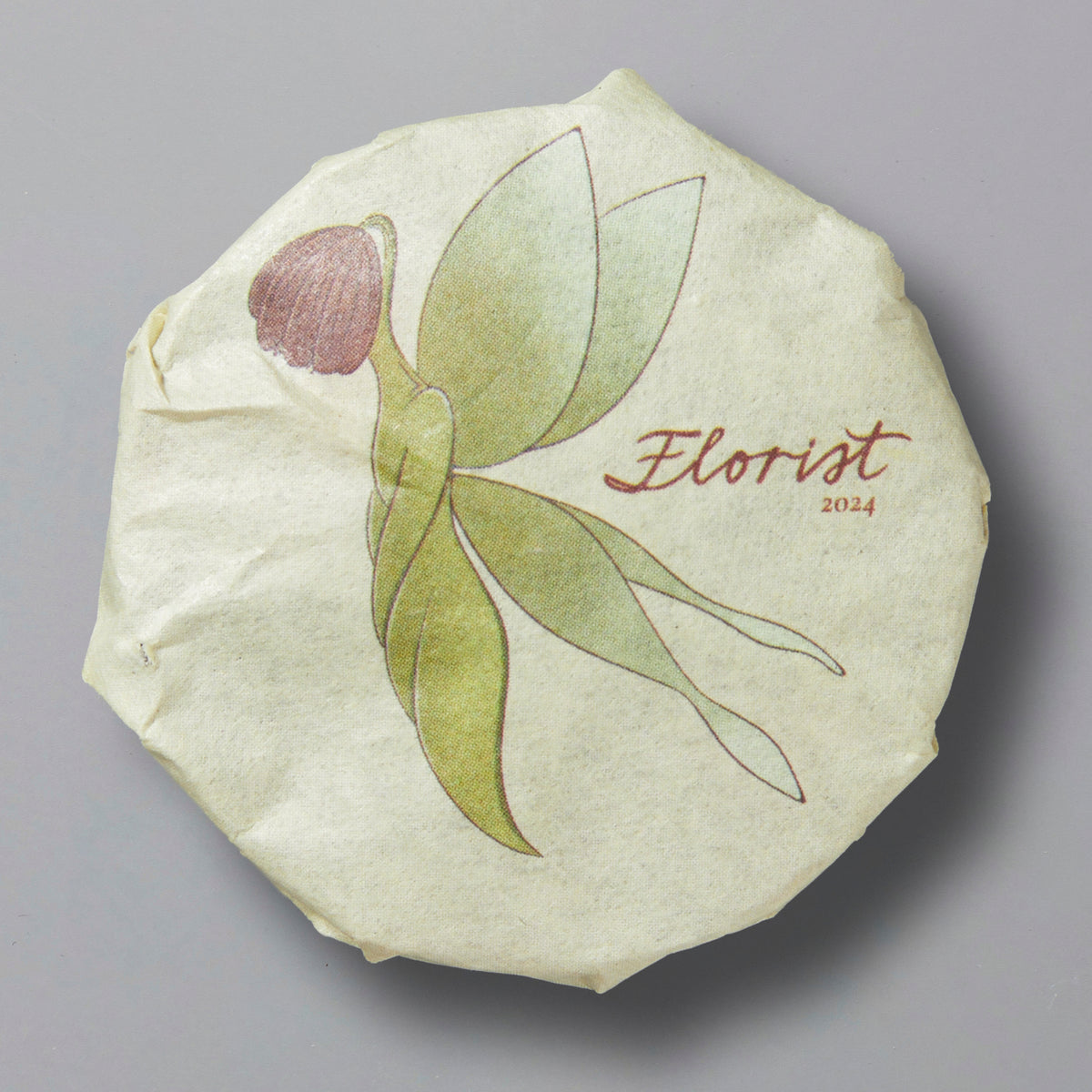 Florist 2024 white tea cake wrapped in paper featuring minimalist floral illustration and product name.