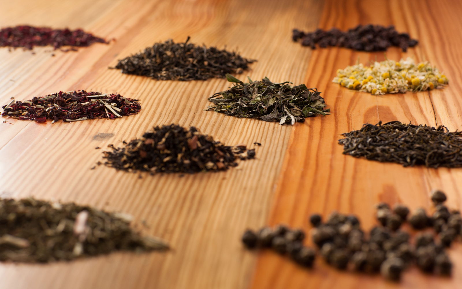 Assorted types of dried teas and tisanes on a wooden surface.