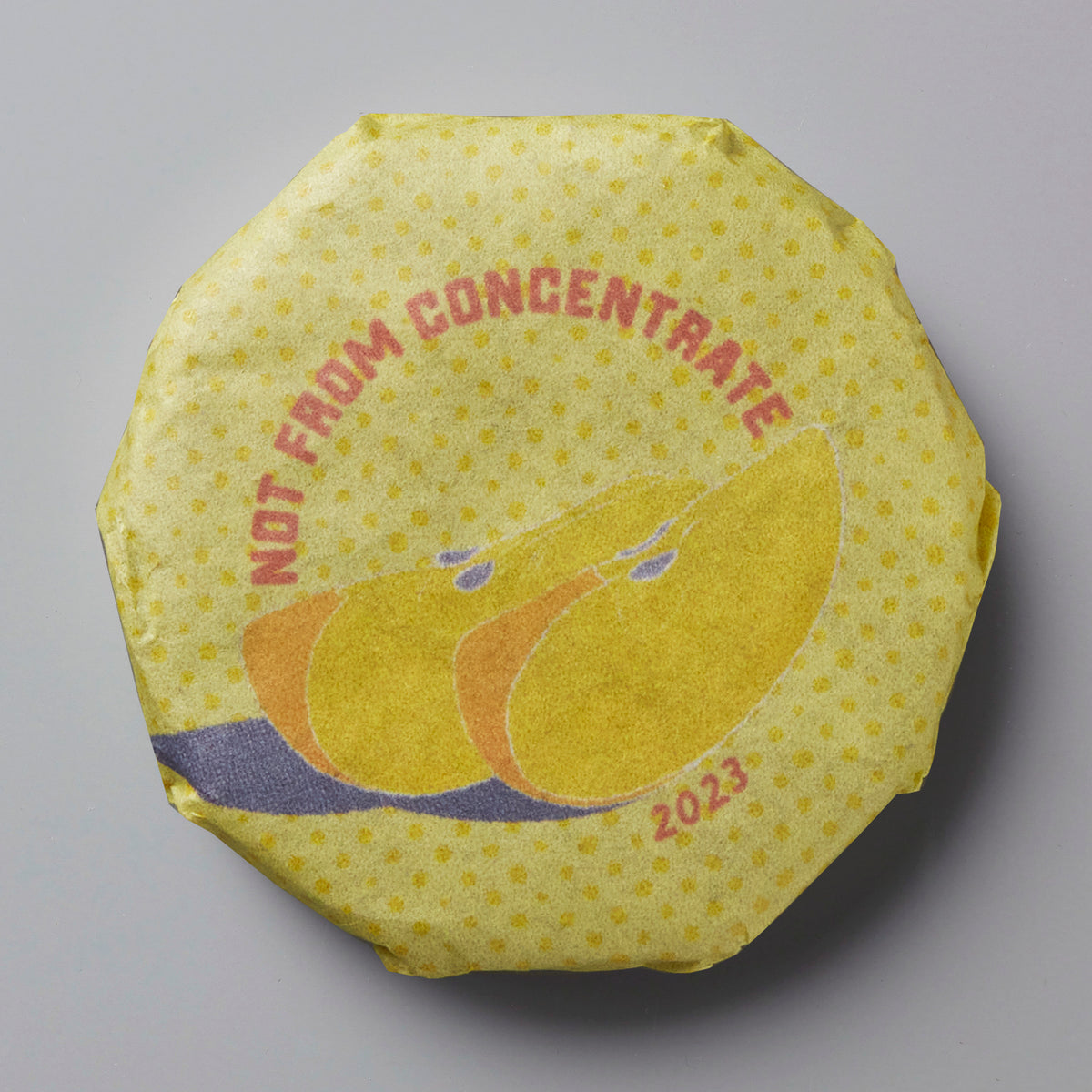 2023 Not From Concentrate white tea cake with yellow wrapper featuring stylized citrus fruit design in orange and yellow