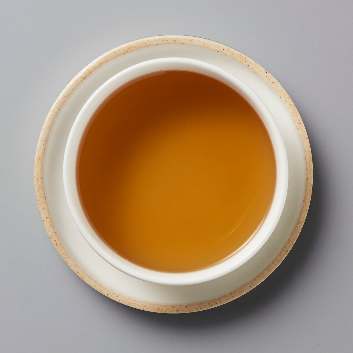2023 Not From Concentrate white tea in ceramic cup showing amber-colored liquid against grey background