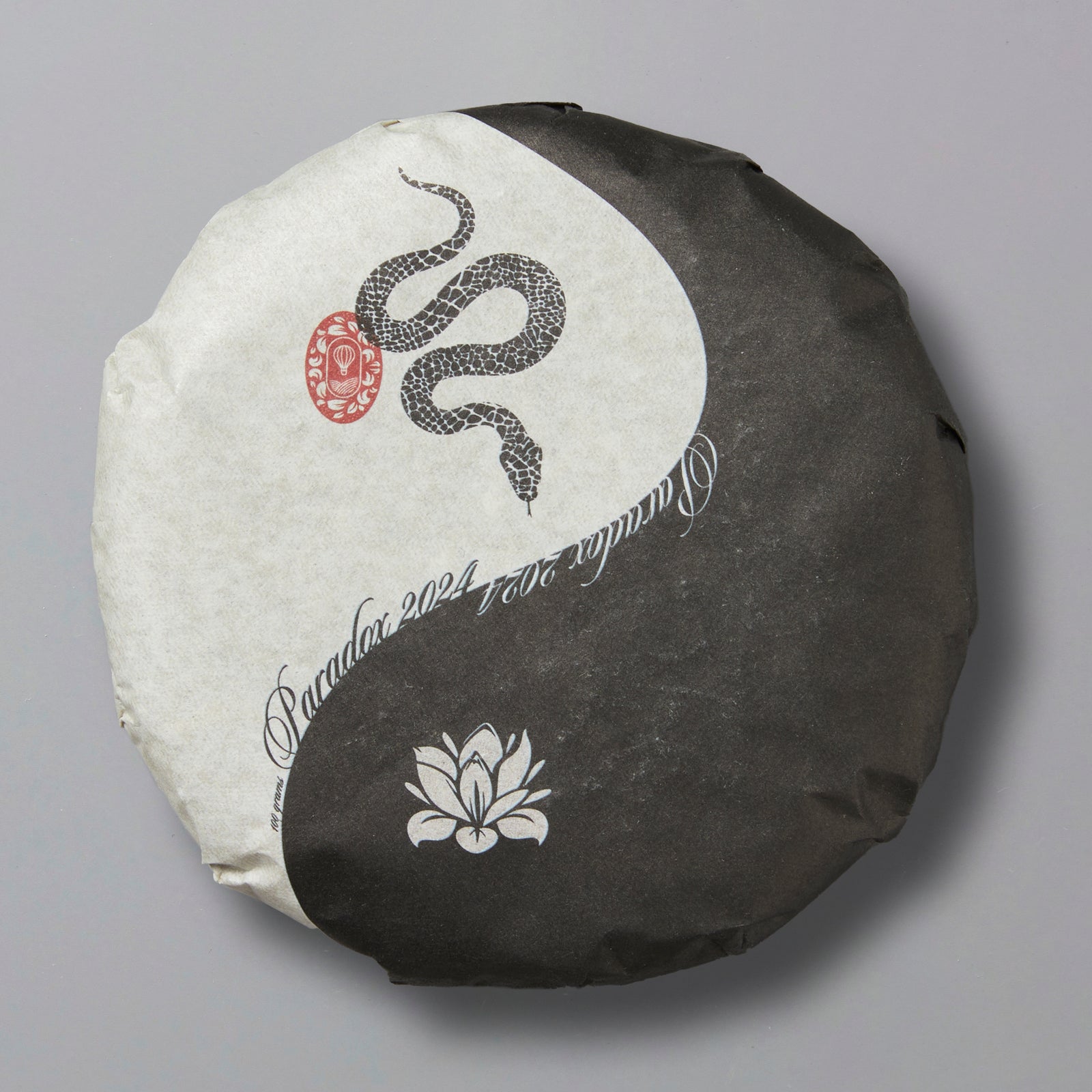 A pressed tea cake with a yin-yang symbol and a floral design, representing the contrast between black and white components.