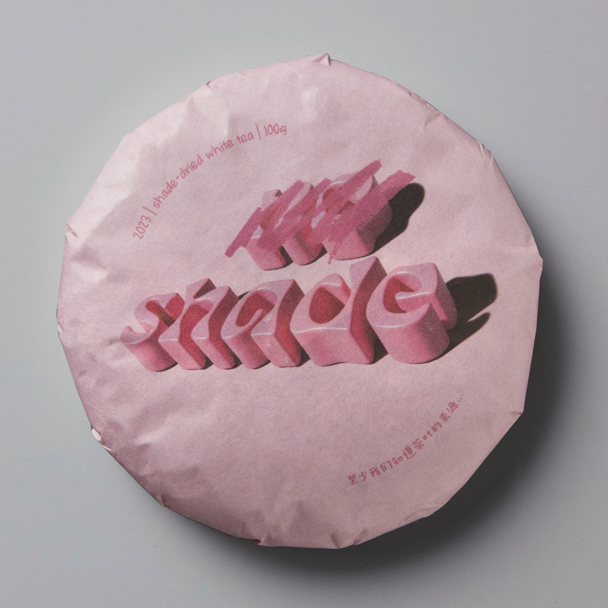 2023 NO SHADE white tea cake in pink wrapper with 3D lettering on circular compressed tea disc