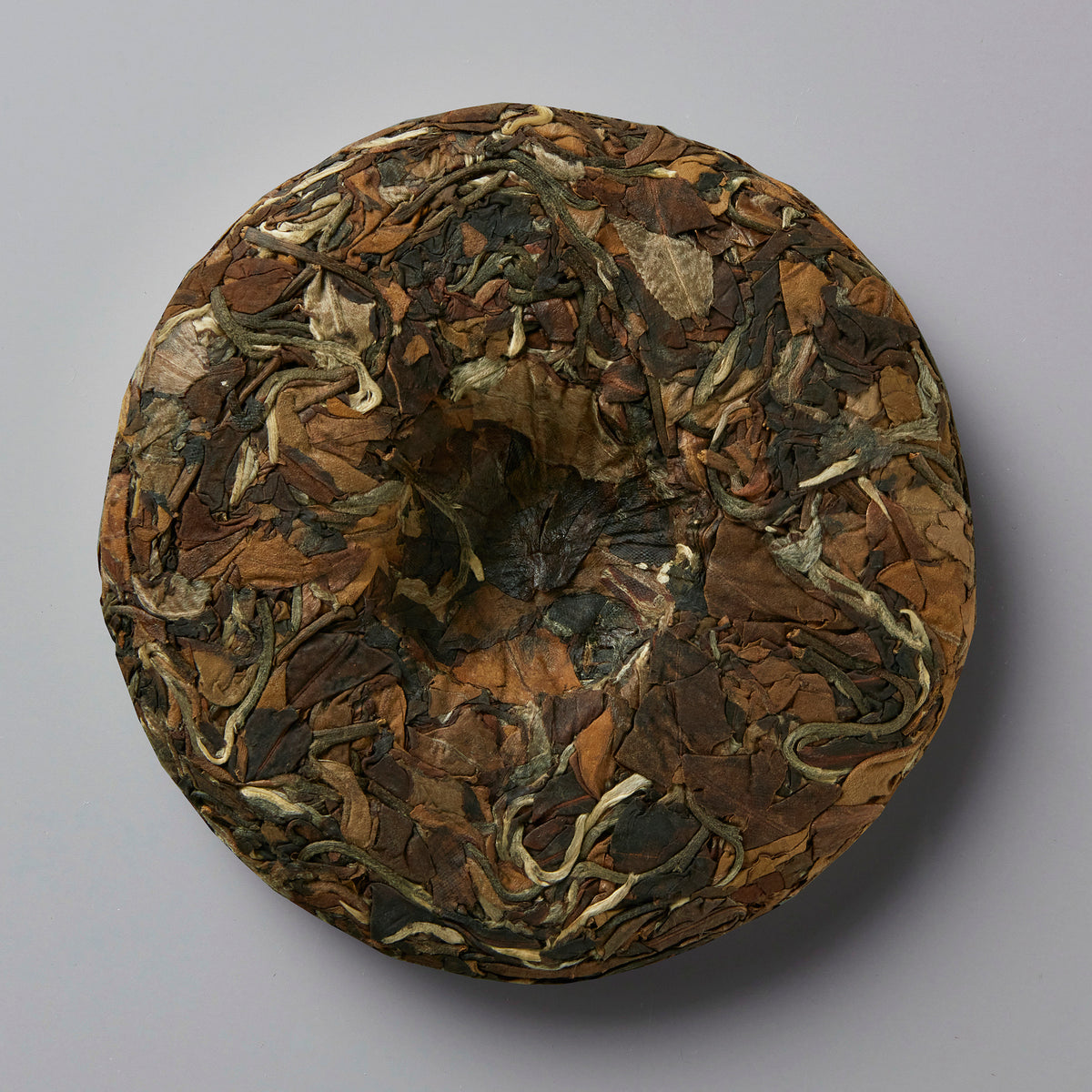 2023 NO SHADE white tea cake with variegated brown and silver leaves compressed into a round disc shape