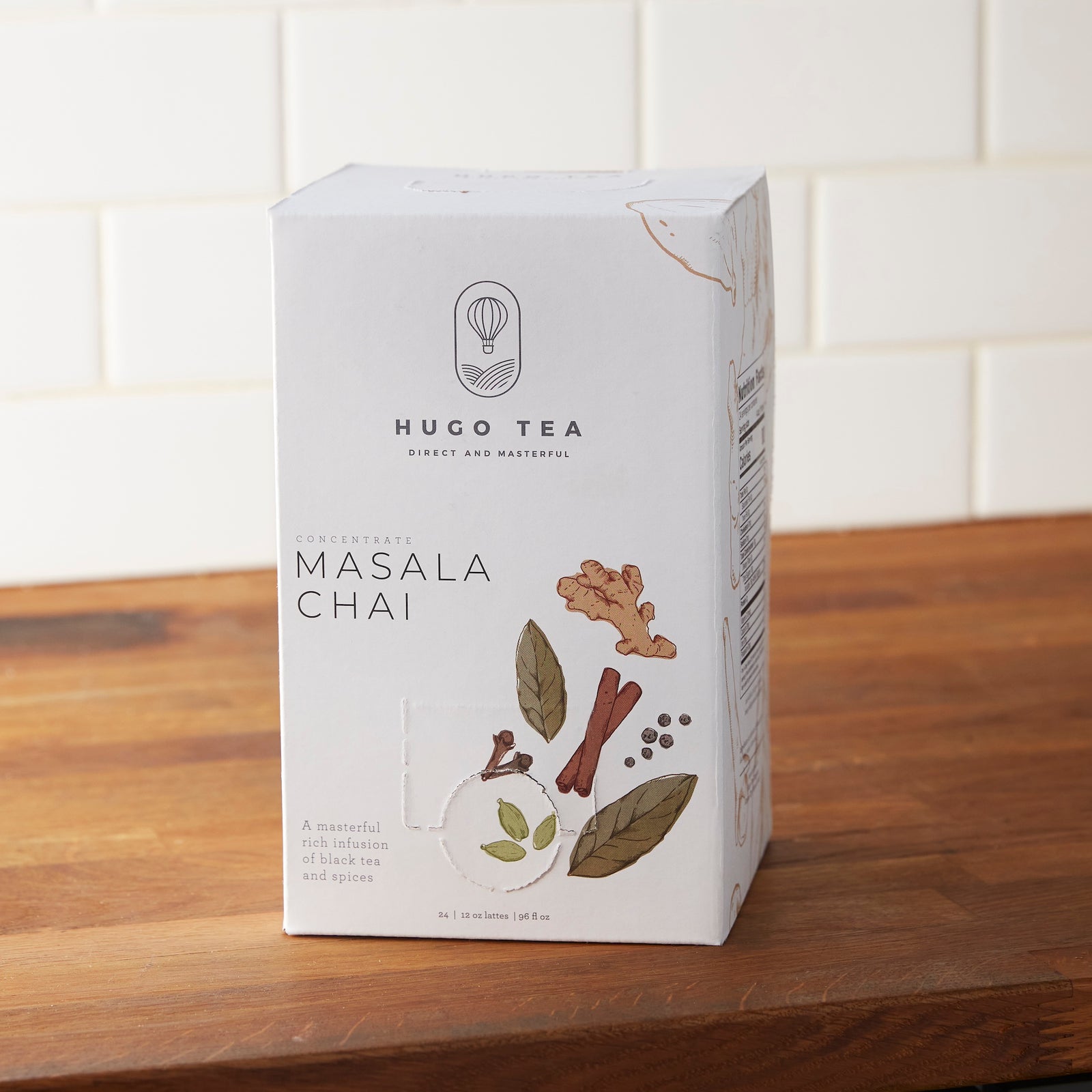 Hugo Tea Masala Chai concentrate box with illustrated spices on white packaging, displayed on wooden surface