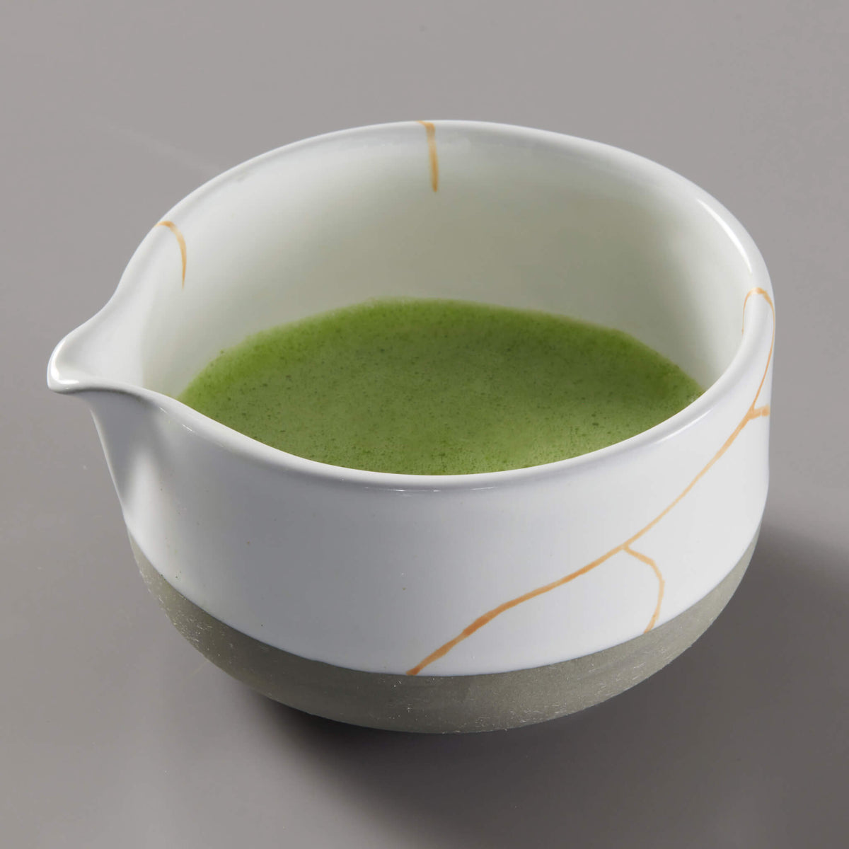 Matcha Bowl KUMO with bright green tea inside white ceramic bowl featuring gold streaks and unglazed base