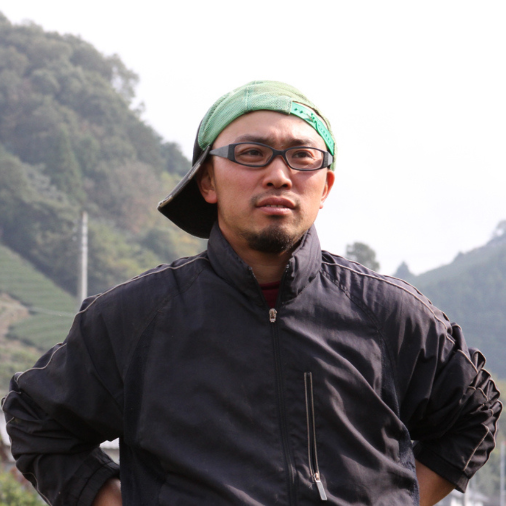 Osamu (sam) wearing a hat and glasses. He is gazing off in the distance with his hands on his hips triumphantly. 