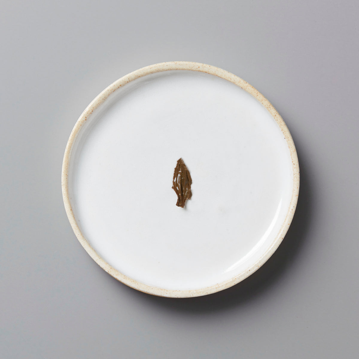 Single black tea leaf from Sam’s Wa-Ko-Sha Okumidori black tea displayed on white ceramic plate