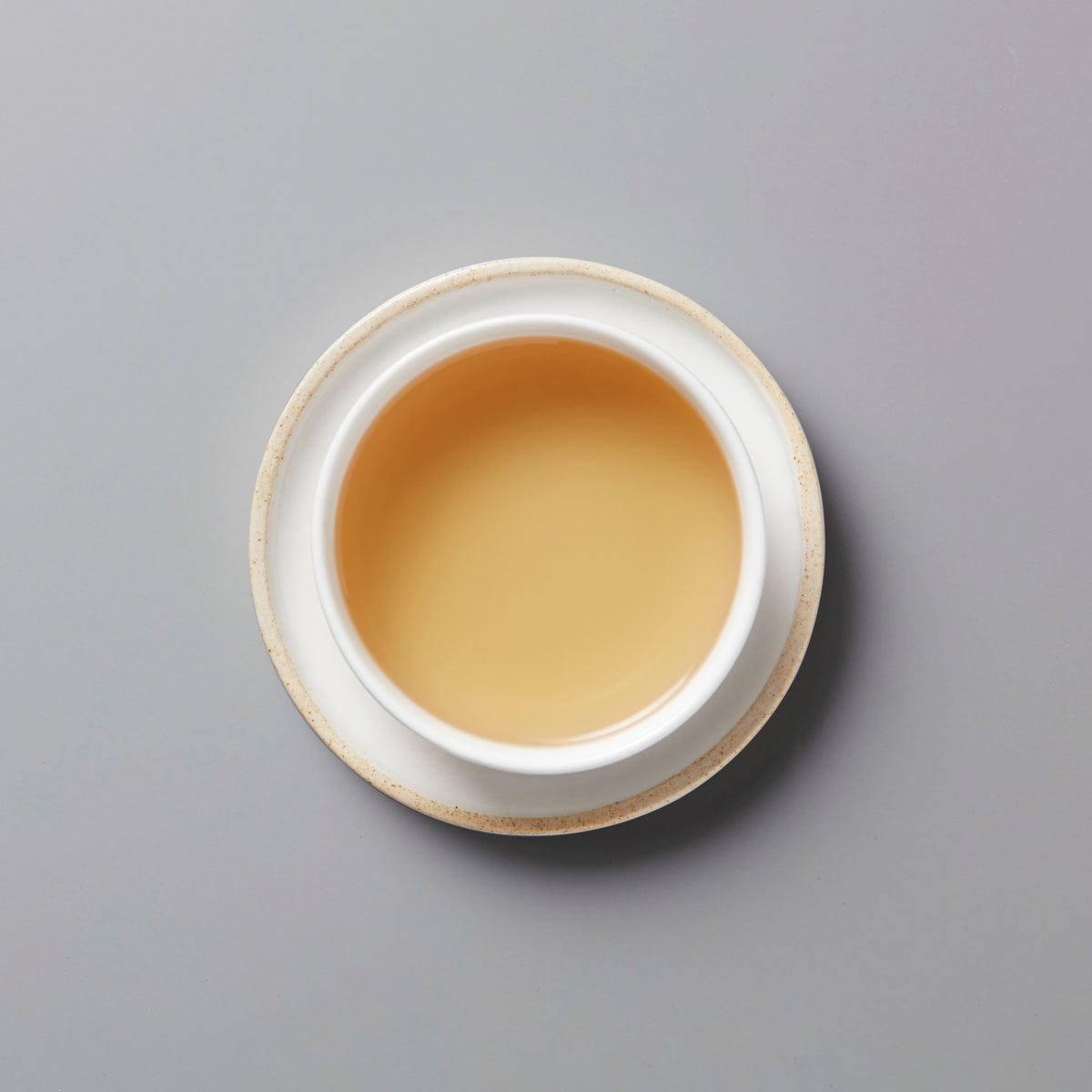 LINS DUCK dancong oolong tea in white ceramic cup with golden amber liquid against grey background
