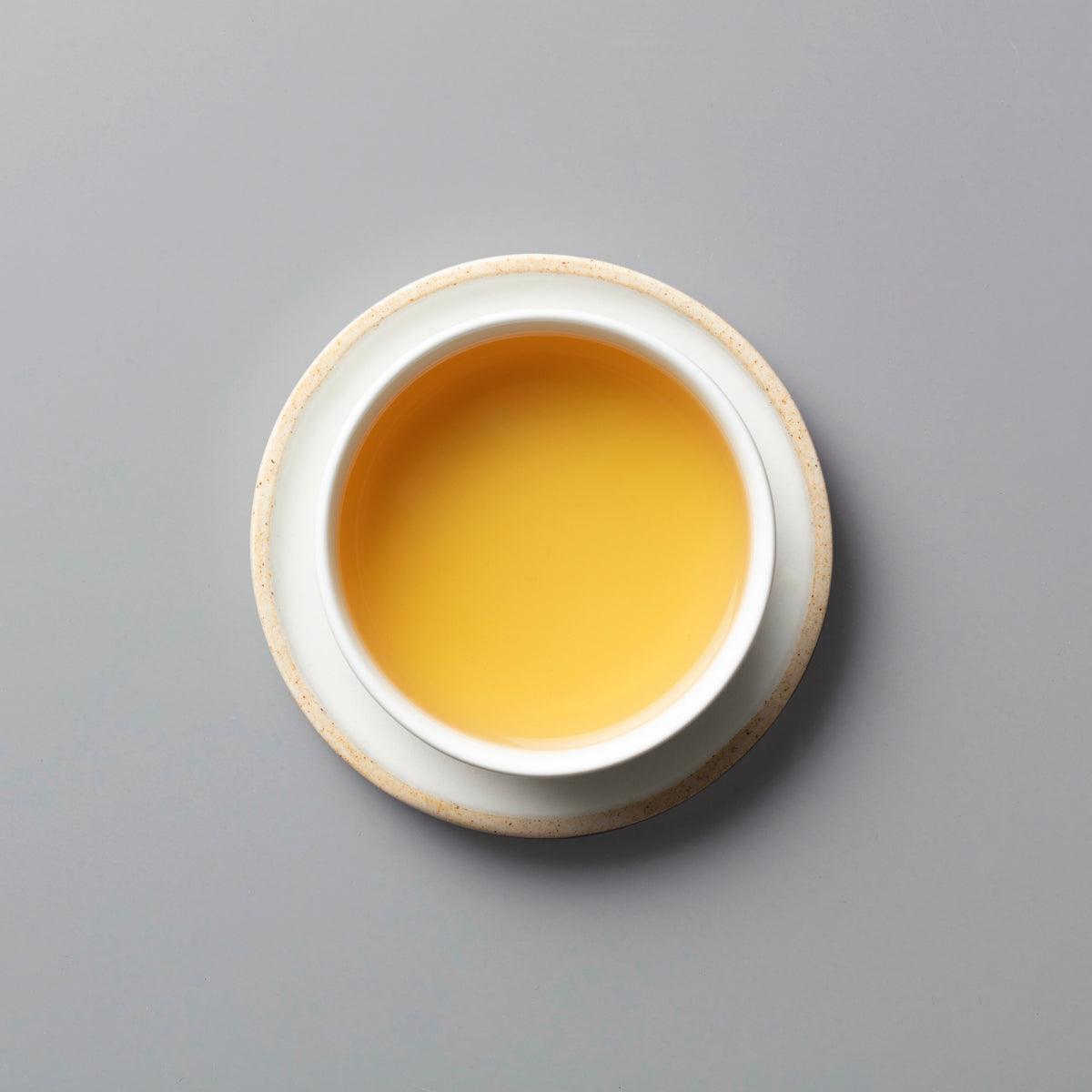 PANLAN QUE SHE yancha oolong tea in white ceramic cup showing golden amber liquid against grey background