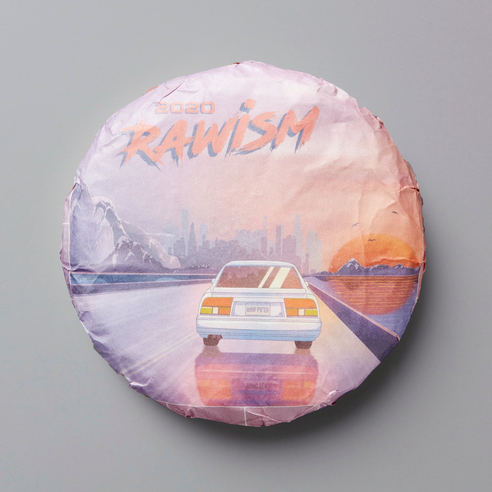 2020 RAWISM sheng puer tea cake with retro sunset design featuring car driving on mountain road