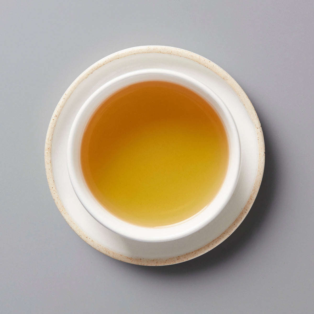 Golden Japanese Tea Flower tisane in white ceramic cup viewed from above, showing amber-colored liquid