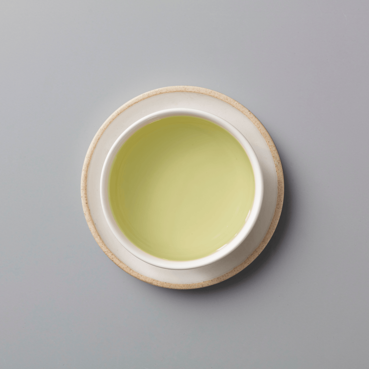 YINYU ANJI BAICHA green tea in white ceramic cup with subtle yellow-green liquor on grey background