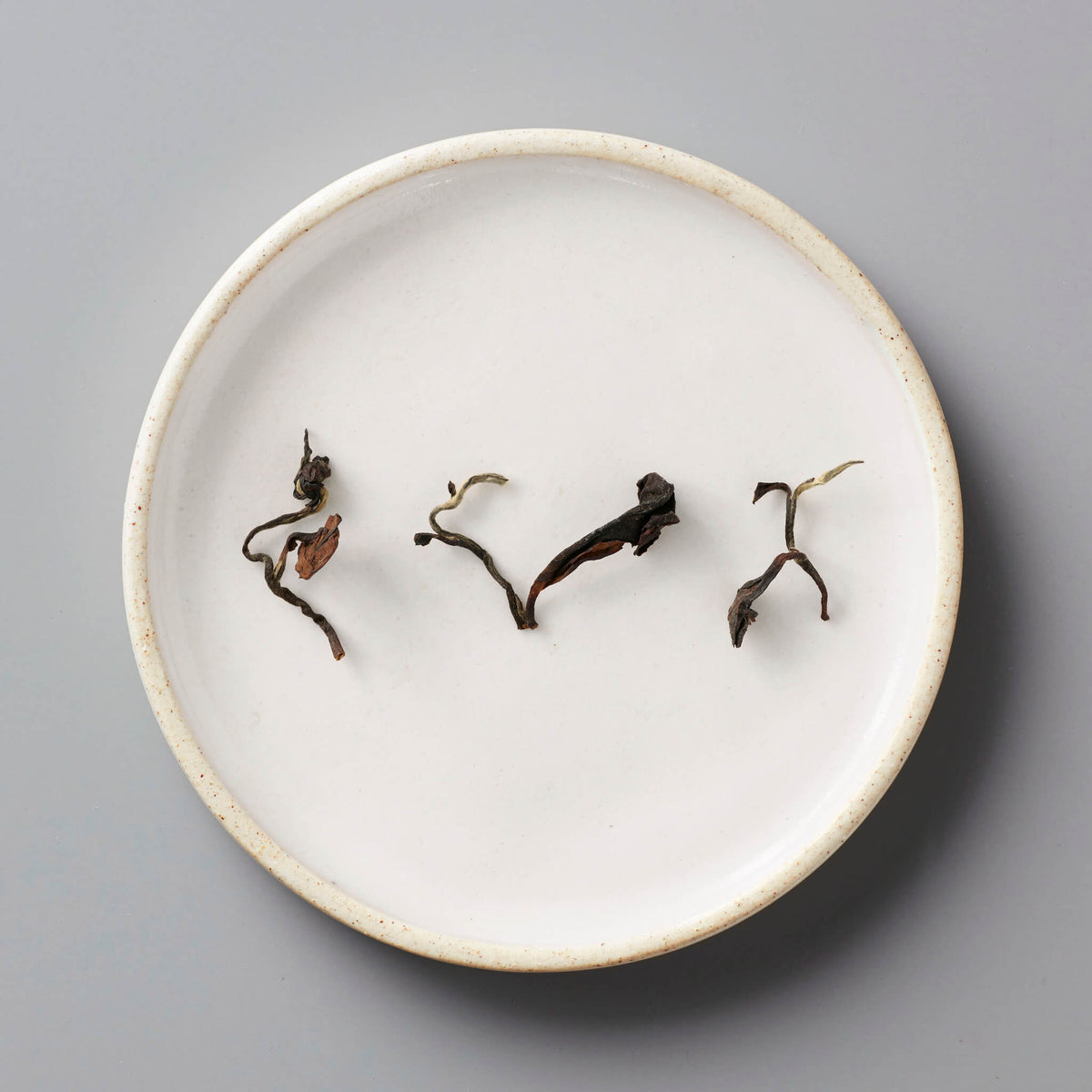 Champagne Long Kou oolong tea leaves artfully arranged on white ceramic plate showing natural twists and curves