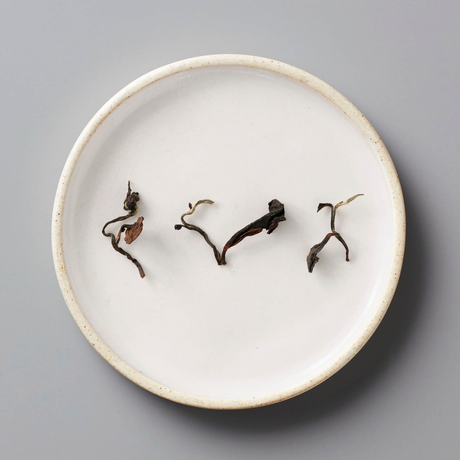 Champagne Long Kou oolong tea leaves artfully arranged on white ceramic plate showing natural twists and curves