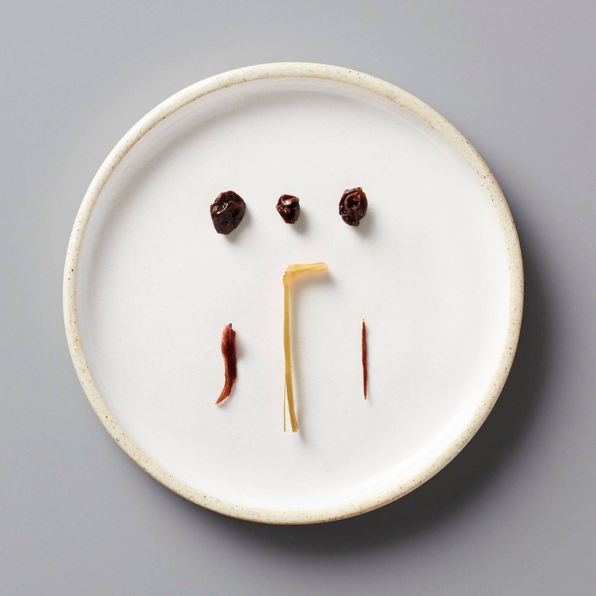 CURRANT tisane blend ingredients artfully arranged on white ceramic plate showing dried currants and herbs