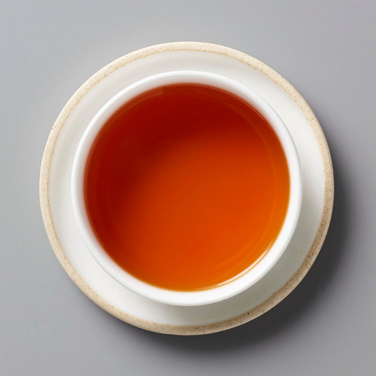 Fyn Rooibos tisane in white ceramic cup showing rich amber-red liquid against grey background