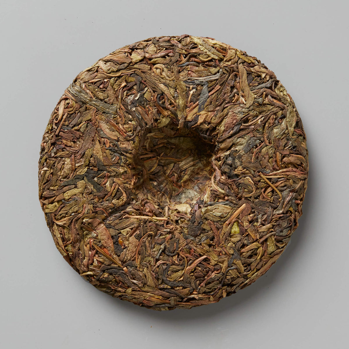 Compressed disc of Grandpas Flask huangpian sheng puer tea showing aged brown leaves and traditional cake shape