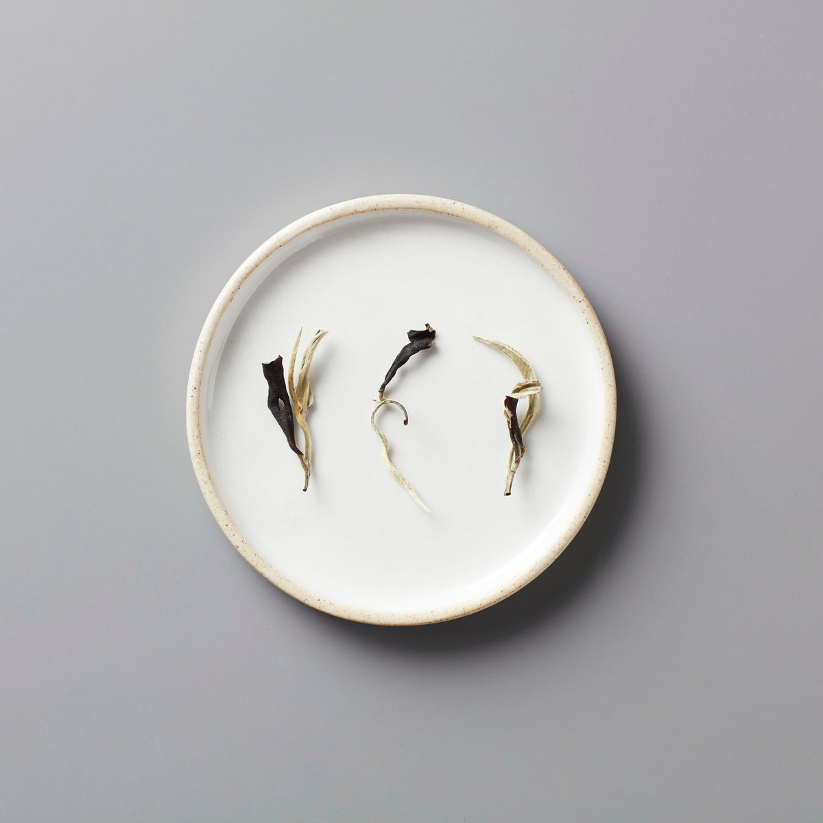 Ma Wei Moonlight white tea leaves displayed on white ceramic plate showing delicate dried buds and leaves arrangement