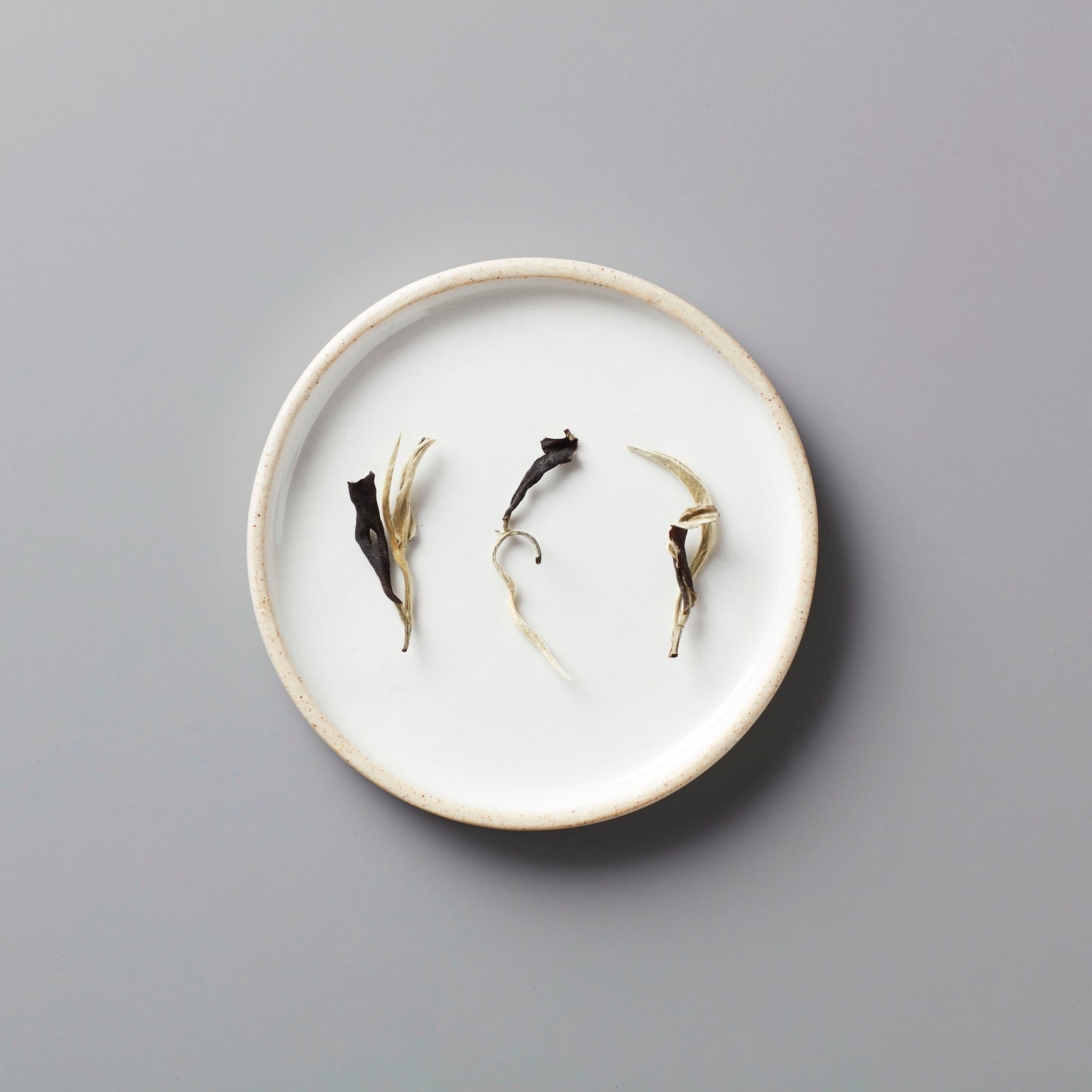 Ma Wei Moonlight white tea leaves displayed on white ceramic plate showing delicate dried buds and leaves arrangement