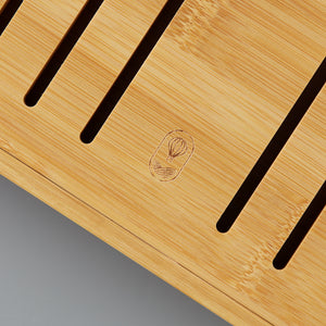 Close-up of natural bamboo tea board with engraved logo and drainage slits for gongfu tea steeping sessions