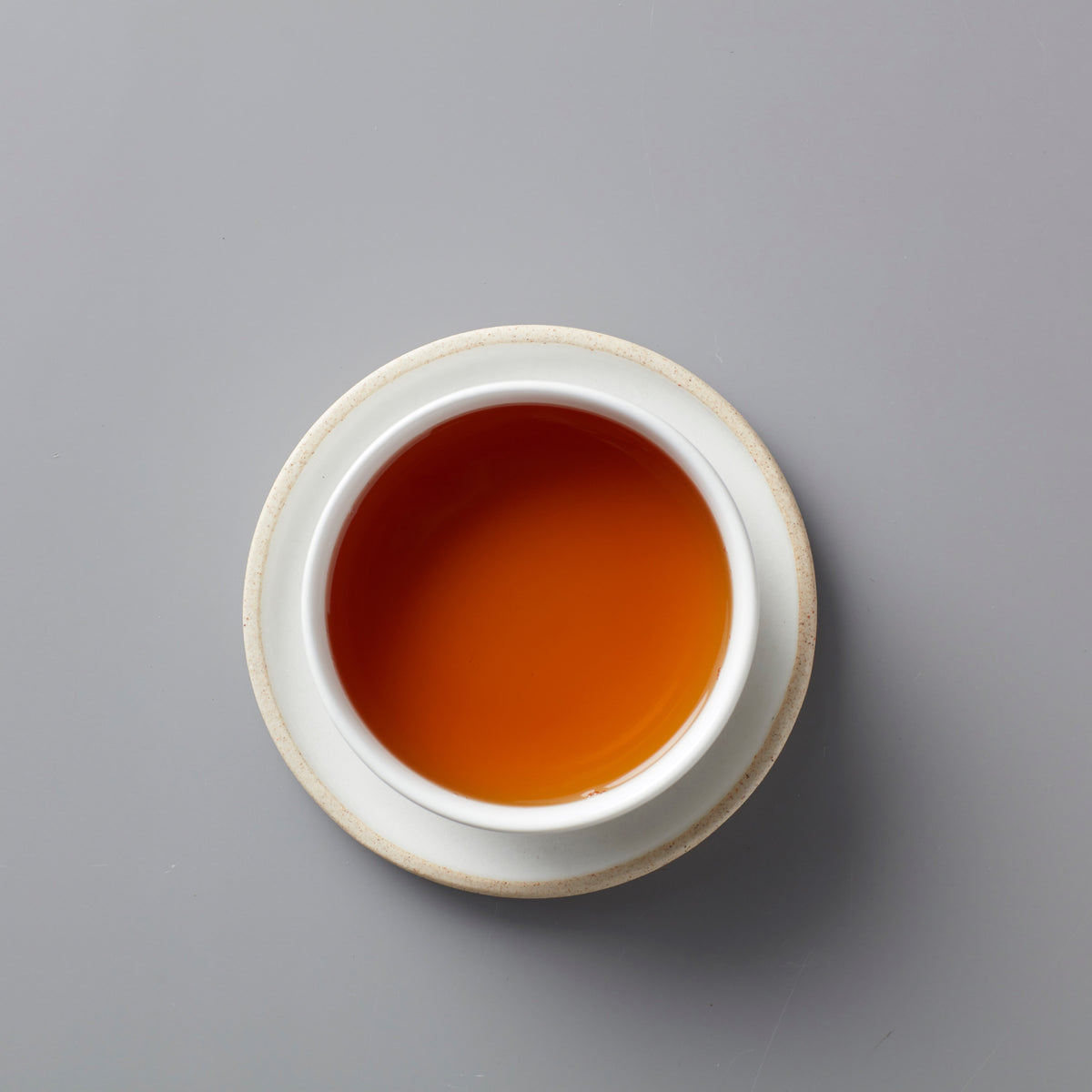 Vanilla Chai black tea blend in white ceramic cup showing rich amber-colored liquor on grey background