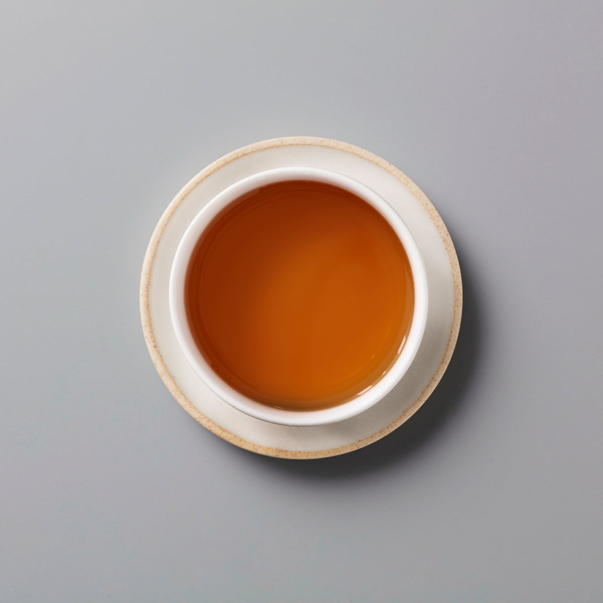 Zi Ran Smoke black tea in white ceramic cup showing rich amber-colored liquor on grey background