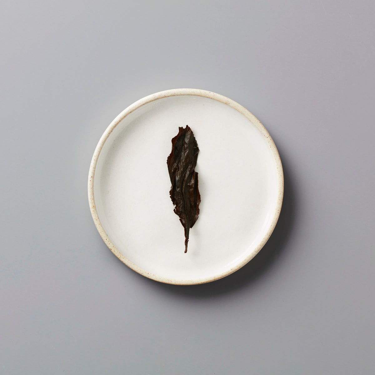 Zi Ran Smoke black tea leaf on white ceramic plate showing natural artisanal lapsang souchong from Tongmu, China